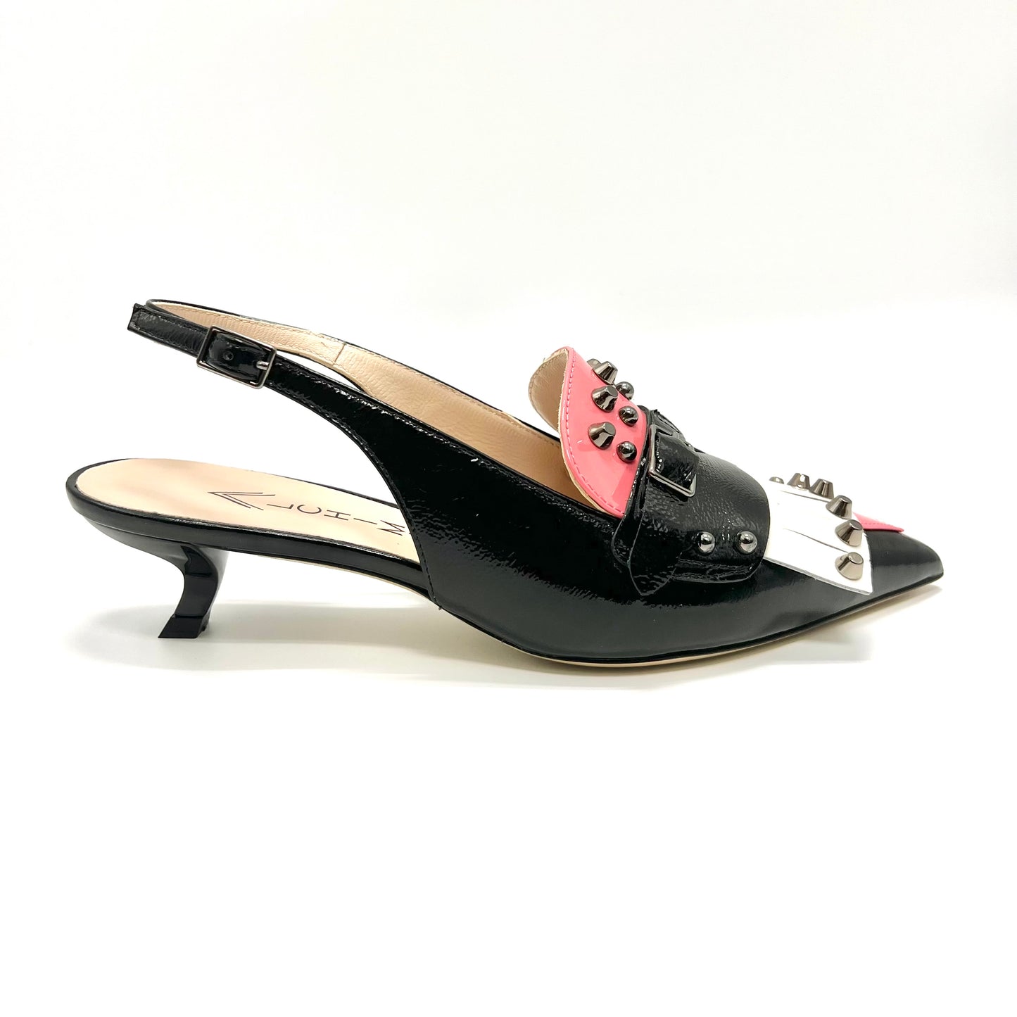Avant-garde slingback pumps feature a striking combination of black, pink, and white patent leather with edgy metal stud embellishments.