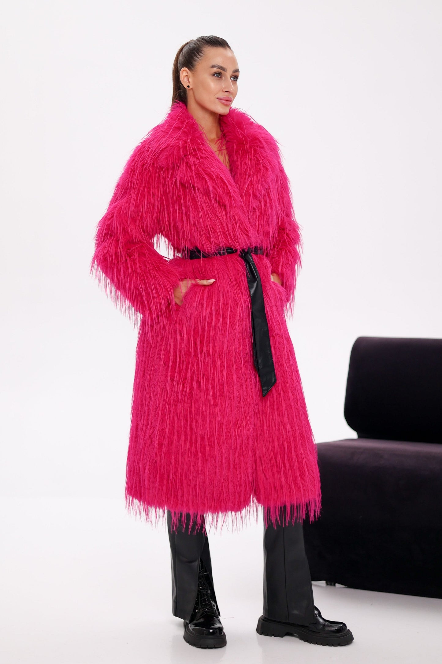 Woman wearing a bright pink fur coat with a white background
