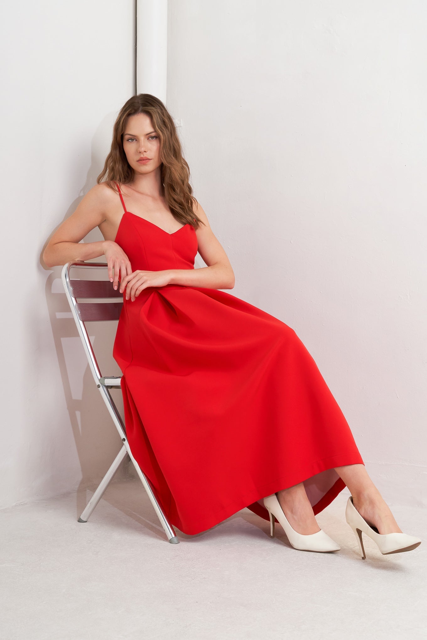 Woman in a red dress sitting on a chair against a white background