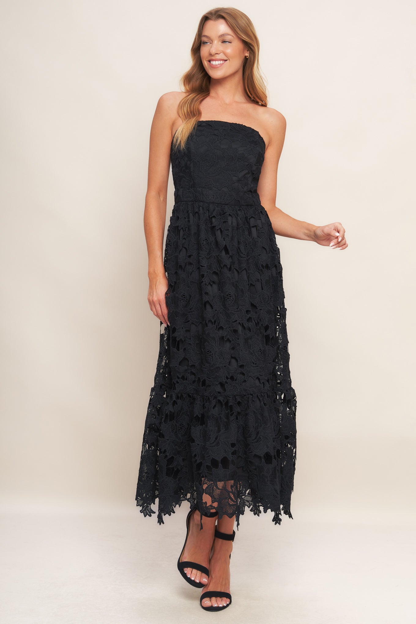 Woman wearing a black lace strapless dress on a plain background